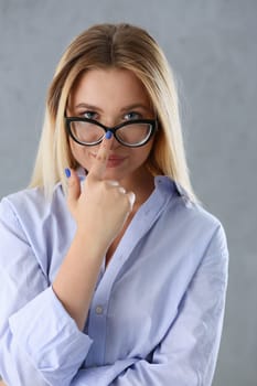 Portrait of a sexy woman in a man's shirt wearing glasses on a gray background looks at the camera and smiling look advice to give wants objections are not accepted.