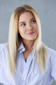 Portrait of a sexy woman in a man's shirt wearing on a gray background looks at the camera and smiling look advice to give wants objections are not accepted.