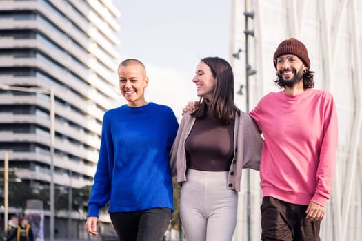 three joyful friends, one man and two women, taking a peaceful stroll together on a sunny day, concept of friendship and urban lifestyle