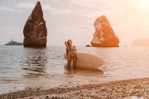 Close up shot of beautiful young caucasian woman with black hair and freckles looking at camera and smiling. Cute woman portrait in a pink bikini posing on a volcanic rock high above the sea