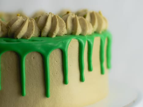 studio shot of green pistachio frosted dripped icing cup cake