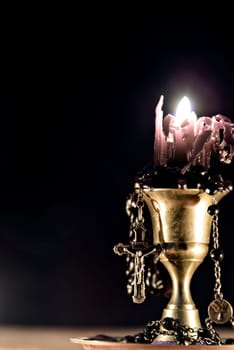 Black candle with rosary on black background