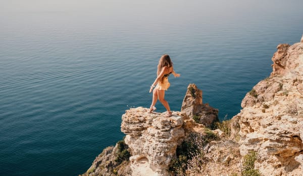 Woman travel sea. Happy tourist taking picture outdoors for memories. Woman traveler looks at the edge of the cliff on the sea bay of mountains, sharing travel adventure journey.