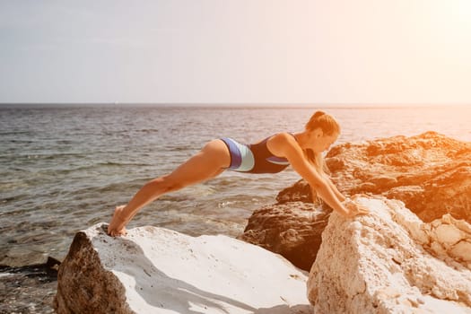 Woman sea yoga. Back view of free calm happy satisfied woman with long hair standing on top rock with yoga position against of sky by the sea. Healthy lifestyle outdoors in nature, fitness concept.