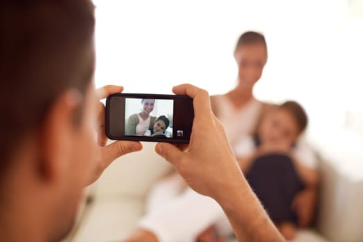 Say cheese. a father taking a picture of his family using his phone