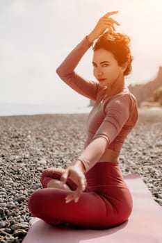 Young woman with long hair in white swimsuit and boho style braclets practicing outdoors on yoga mat by the sea on a sunset. Women's yoga fitness routine. Healthy lifestyle, harmony and meditation