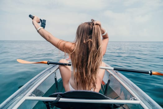 Woman in kayak back view. Happy young woman with long hair floating in transparent kayak on the crystal clear sea. Summer holiday vacation and cheerful female people having fun on the boat.