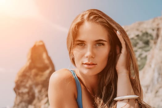 Woman travel sea. Young Happy woman in a long red dress posing on a beach near the sea on background of volcanic rocks, like in Iceland, sharing travel adventure journey