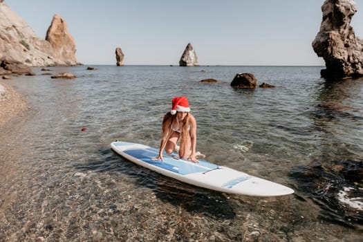 Close up shot of happy young caucasian woman looking at camera and smiling. Cute woman portrait in bikini posing on a volcanic rock high above the sea