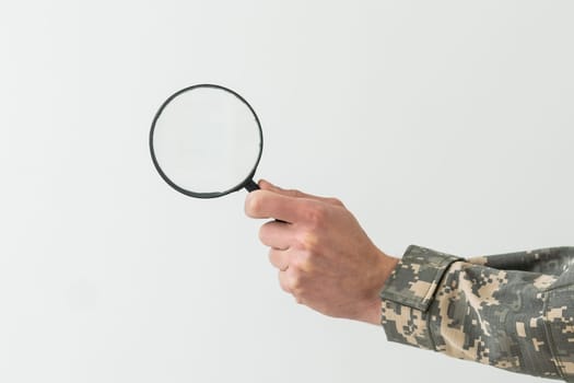 soldier holding magnifying glass in office.