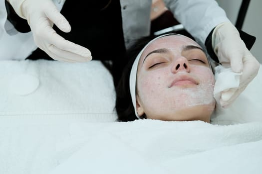 Cosmetologist cleaning woman's face before applying face treatments . Preparing patient's skin before treatment.