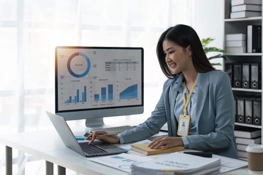 Businesswoman sits at work with laptop and computer and analyzes corporate and tax activities at office.