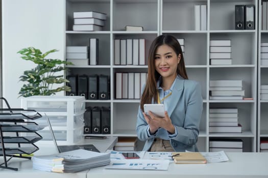 Businesswoman sits at work with laptop and computer and analyzes corporate and tax activities at office.