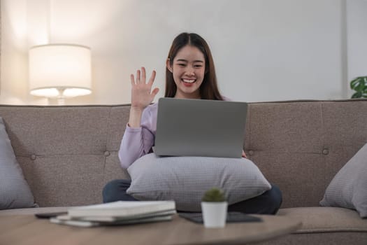 Woman having video call on her laptop at home. Smiling girl smile to family or friends.