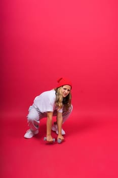 Kid girl doing fitness exercises with dumbbells on a red background