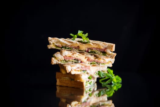 fried toasts stuffed with sausage, cheese and greens inside, isolated on black background.