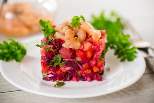 vinaigrette salad of boiled vegetables with salted fish in a plate, on a wooden table.