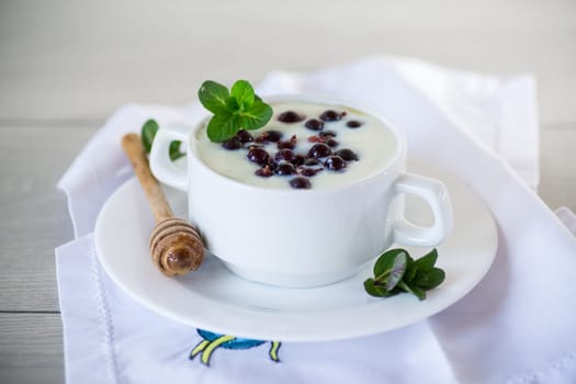 Cooked milk semolina porridge with berries and honey in a plate, on a wooden table.