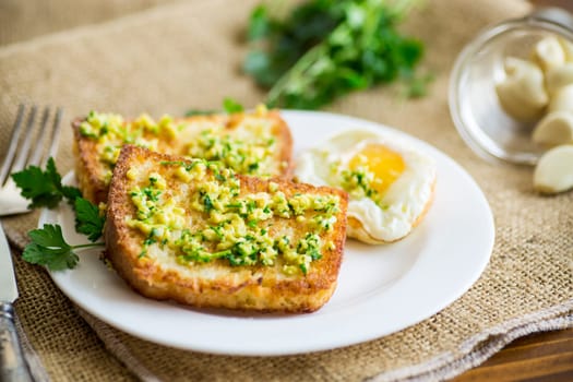 Fried croutons in batter with garlic and herbs in a plate, on a wooden table.