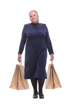 Caucasian senior woman walking with shopping bags smiling at viewer. Concept of successful shopping