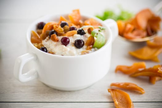 oatmeal with candied fruits, raisins in a plate on a wooden table.