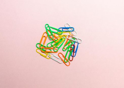 Office paper clips isolated on colored background. Pink, red, blue, green, orange colorful Plastic paperclips documents staple attach tools.
