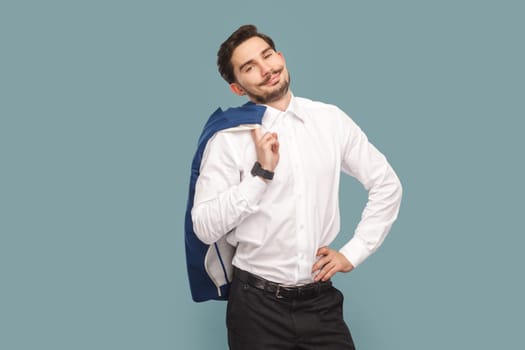 Portrait of satisfied smiling confident man with mustache standing holding his jacket over shoulder, looking at camera, wearing Indoor studio shot isolated on light blue background.