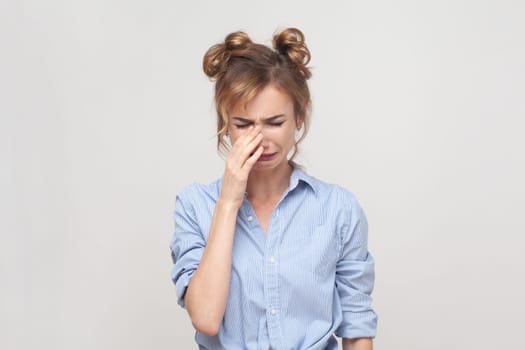 Portrait of displeased upset blonde woman frowning face, crying, being discontent and unhappy as cant achieve goals, wearing blue shirt. Indoor studio shot isolated on gray background.