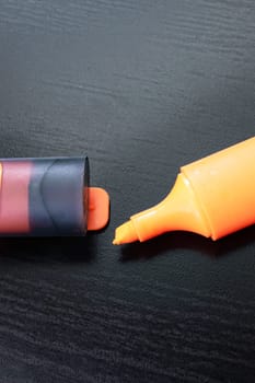 Orange marker on a black wooden table close up