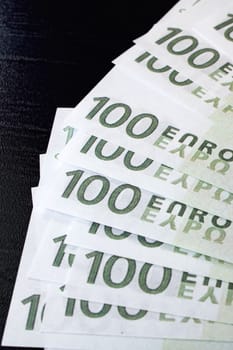Fanned out bills of one hundred euros on black background