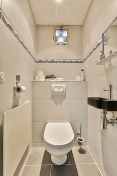 a white toilet in a small bathroom with grey tiles on the walls, and a mirror above the toilet bowl