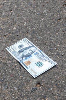 Crumpled one hundred dollar bill on the pavement