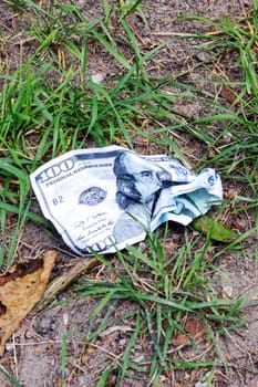 Crumpled one hundred dollar bill on the ground