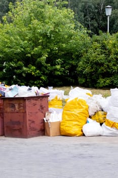 Trash cans and large white garbage bags outdoors