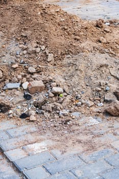 A pile of construction sand on a tiled sidewalk