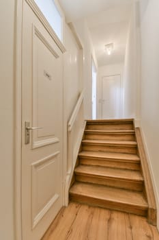 an empty hallway with wooden floors and white door leading to the second floor in a house or condo apartment building