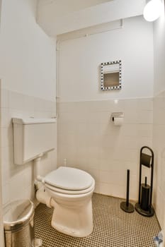 a white toilet in a bathroom with black and white tiles on the floor next to it is a trash can