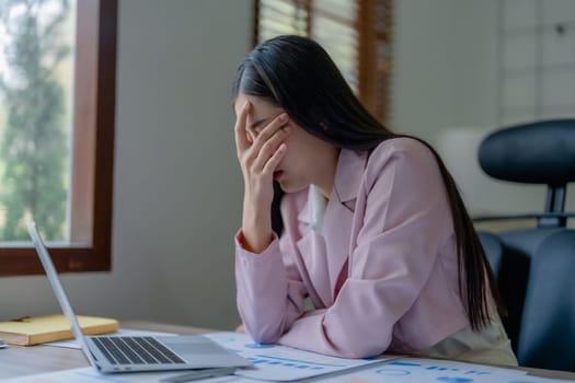 Portrait of a young Asian woman showing acute headache from sitting for a long time at work