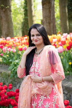 A beautiful Indian woman with black hair in a national Indian pink sari dress against the background. High quality photo