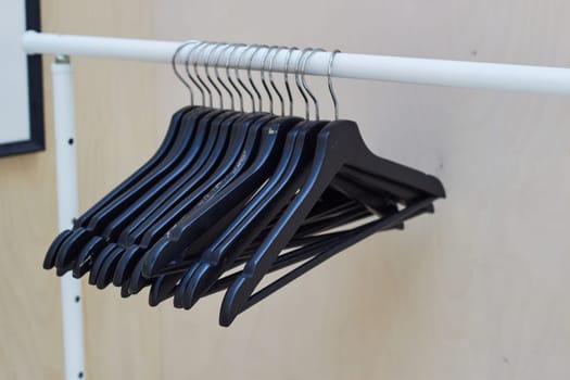 black wooden clothes hangers hang on a rail. Presentation of clothes. Hanger for buyers. Clothes fitting.