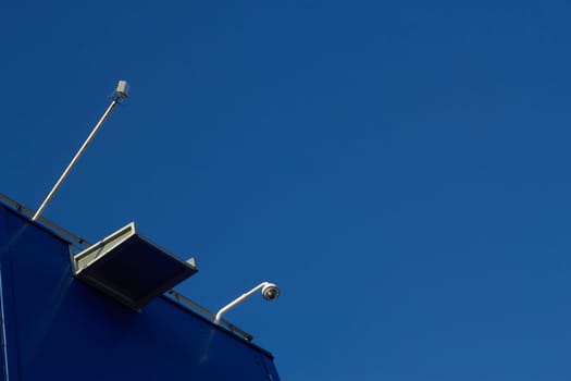Surveillance cameras on the roof of a retail space against a clear blue sky. Tranquility and serenity. Protection.