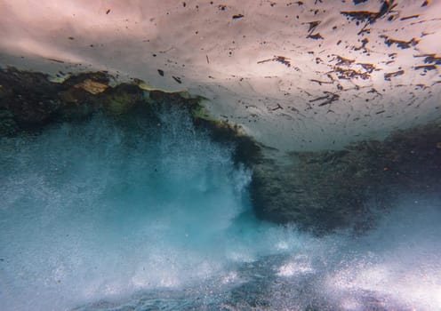 A calming and abstract underwater view with sand floor, a waterfall, and waves. The image is upside down, making the sand appear like the sky and the water like the ground.