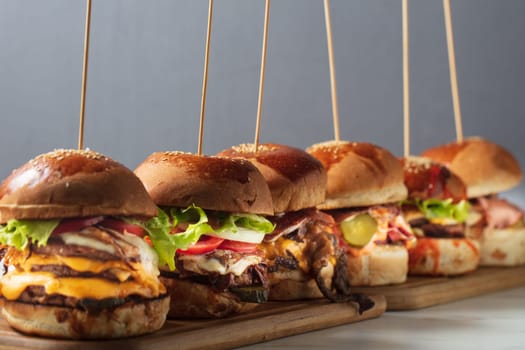 Many different burgers with ingredients on a wood plate. High quality photo