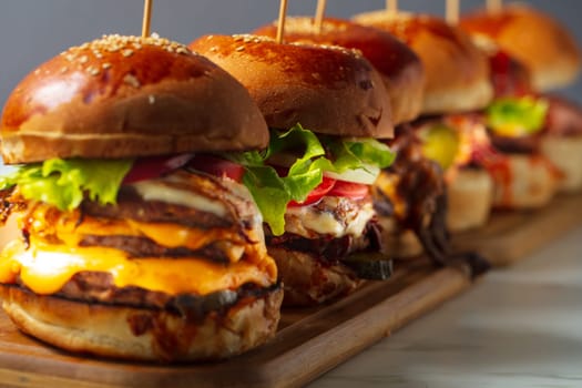 Many different burgers with ingredients on a wood plate. High quality photo