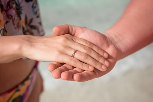Man and woman, newlyweds holding hands with blurred background close-up.