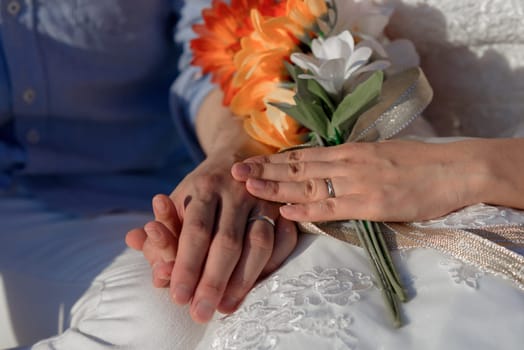 Man and woman, newlyweds holding hands with blurred background close-up.
