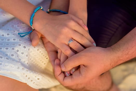 Man and woman, newlyweds holding hands with blurred background close-up.