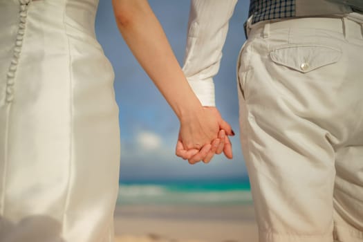 A man and a woman held hands against backdrop of the sea close-up.