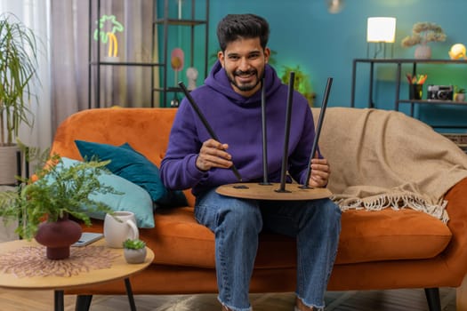 Happy indian man finishing assembling furniture at home. Successful table desk collect repair fixing. Hindu guy after moving into new apartment. Advertisement of a furniture store. Mortgage, lifestyle