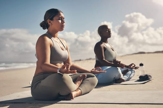 Yoga helps you to become a better version of yourself. two young women meditating during their yoga routine on the beach